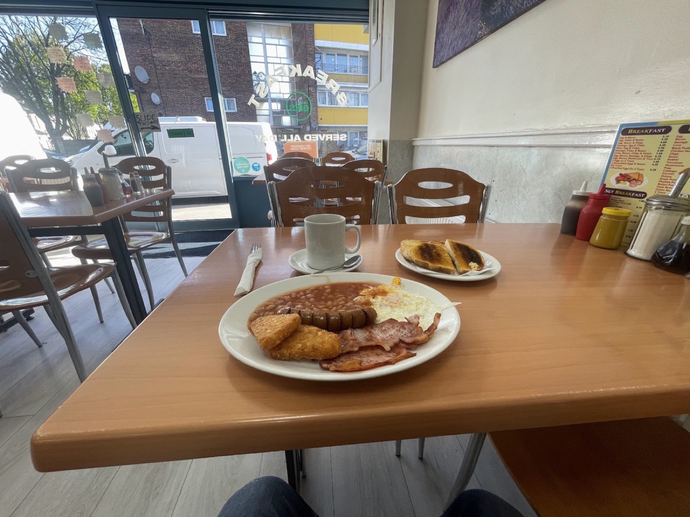 Breakfast plate on a table by the window, with the Plaistow Cafe frontage and street beyond