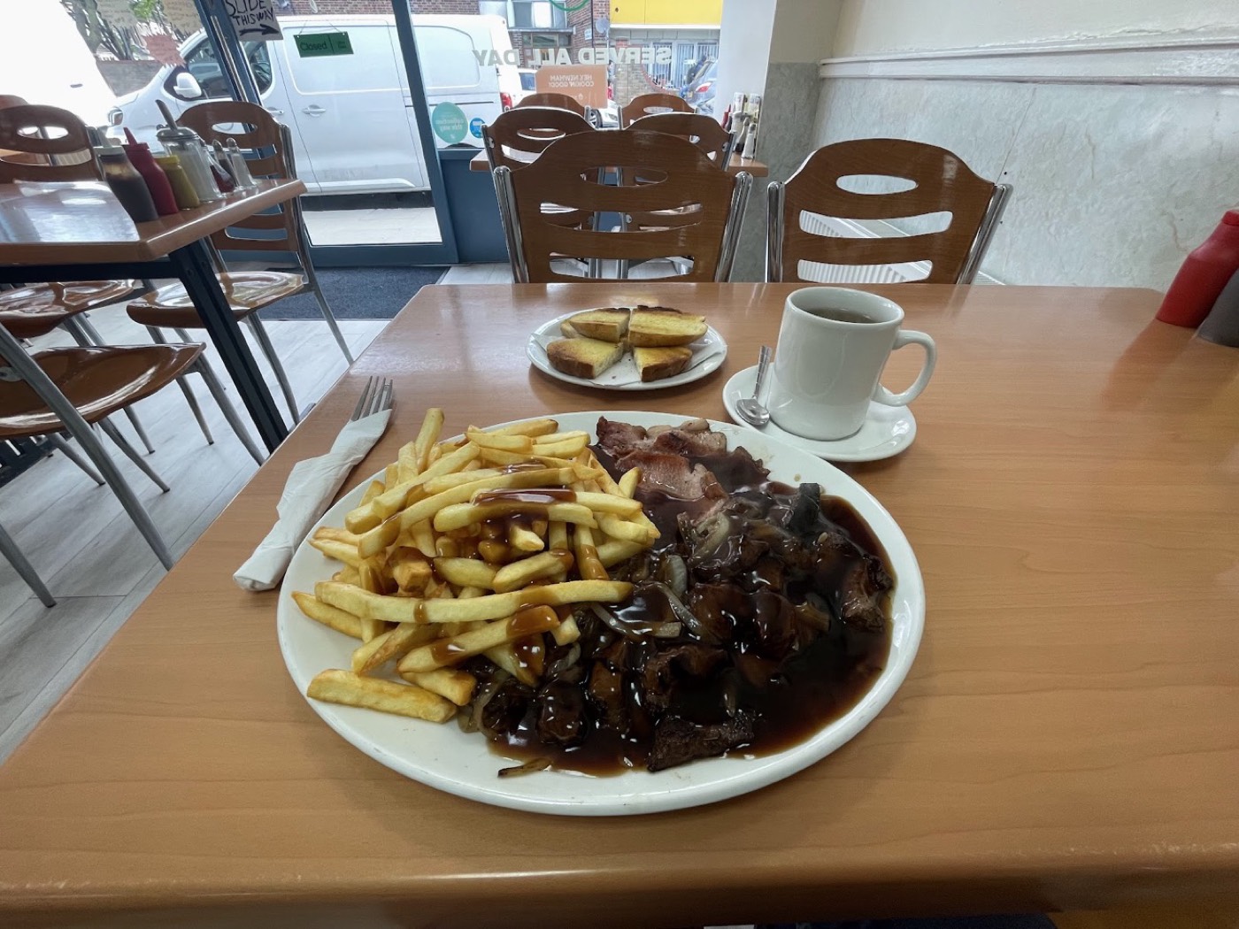Steak and chips with onion gravy and a mug of tea by the window at Plaistow Cafe