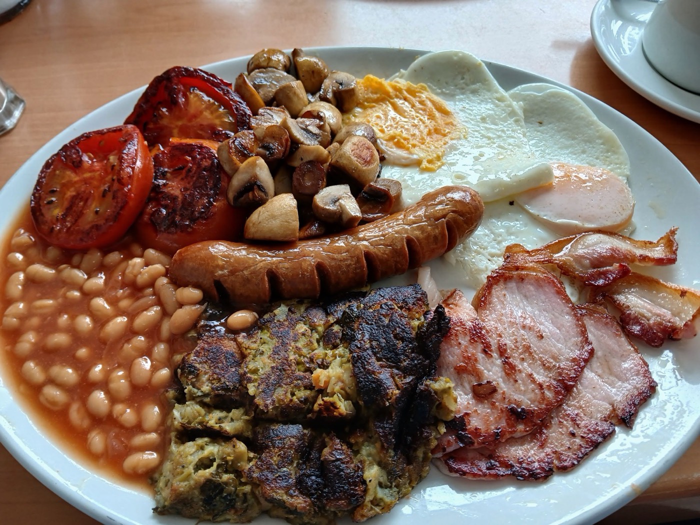A loaded full English breakfast at Plaistow Cafe — sausage, bacon, eggs, beans, mushrooms, grilled tomato and hash browns